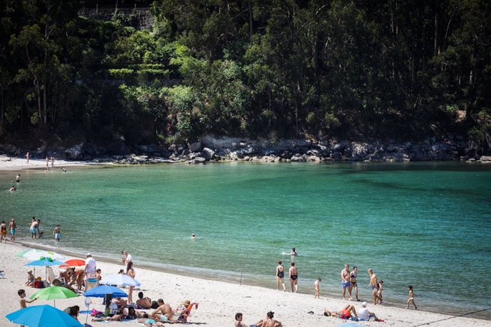 Varias personas se bañan y toman el sol en una playa del municipio de Marín.