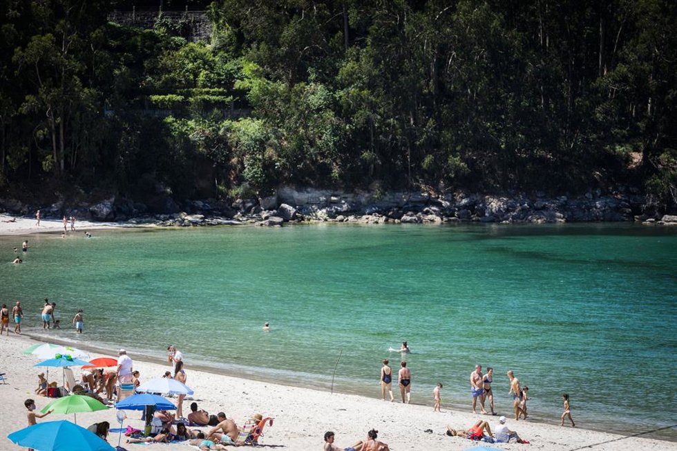 Varias personas se bañan y toman el sol en una playa del municipio de Marín.