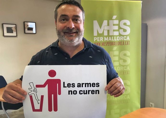 El diputado de MÉS Joan Mas sostiene un cartel con el lema 'Las armas no curan'.