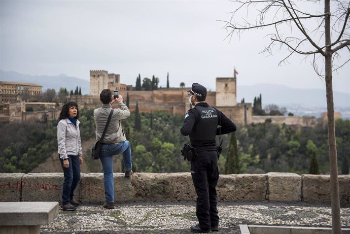 Archivo - 15 March 2020, Spain, Granada: A policeman asks two tourists to leave the San Nicolas viewpoint in Granada during the Coronavirus (Covid-19)lock down. Spain has imposed a two-week so-called state of alert throughout the country to combat the 
