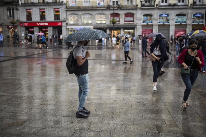 Ciudadanos se resguardan de la lluvia a 5 de junio de 2021, en Madrid (España)