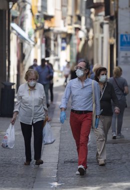 Varias personas caminan protegidas con mascarillas por una calle del centro de la ciudad. En Sevilla, (Andalucía, España), a 19 de mayo de 2020.