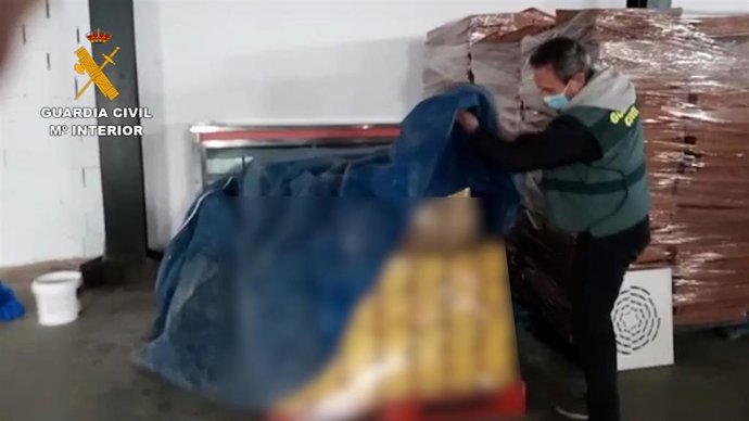 Un agente de la Guardia Civil con el whisky incautado.