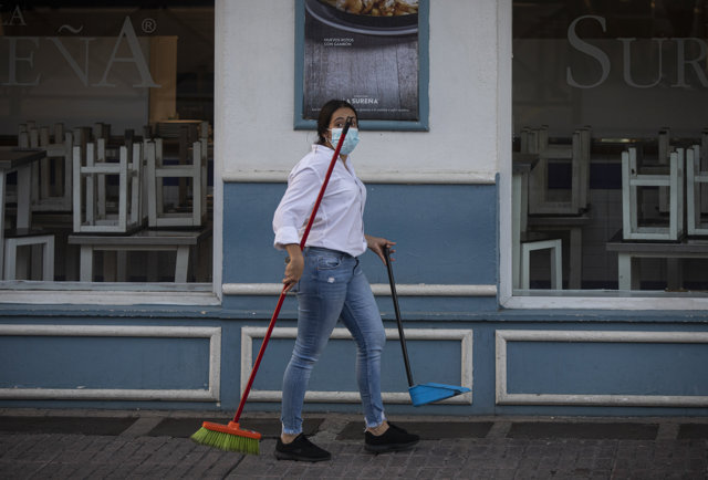 Una camarera tras recoger el mobiliario de la terraza de un bar
