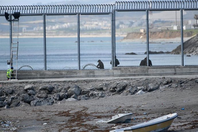 Agentes de la Gendarmería Real marroquí y Fuerzas auxiliares (Mejania) levantan alambradas de concertinas en la parte inferior del vallado en el espigón del Tarajal, a 1 de junio de 2021