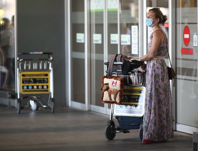 Una mujer protegida con mascarilla llega con su equipaje a la Terminal T1 del Aeropuerto Adolfo Suárez Madrid-Barajas el día de su apertura y de las fronteras de España, en Madrid (España), a 1 de julio de 2020. 