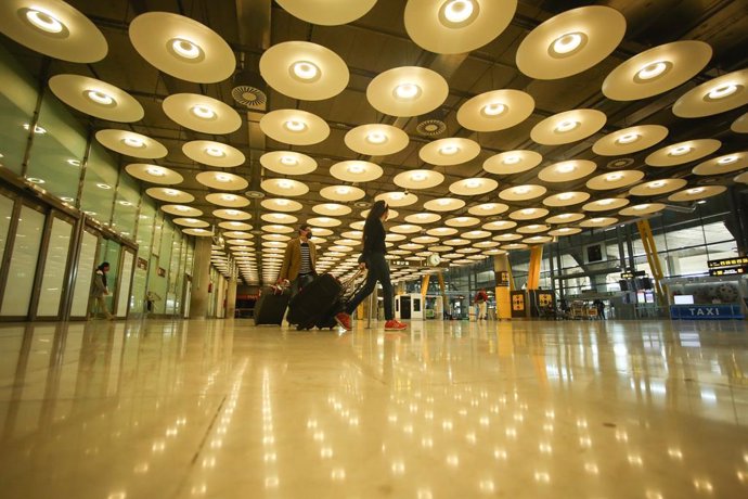 Archivo - Dos personas caminan con su equipaje en la Terminal T4 del Aeropuerto Adolfo Suárez Madrid-Barajas, en Madrid (España), a 15 de marzo de 2021. El Gobierno ha prorrogado hasta el próximo 30 de marzo la limitación de los vuelos directos y buques