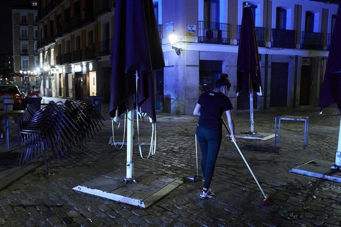Una trabajadora recoge la terraza de una cafetería de Madrid 