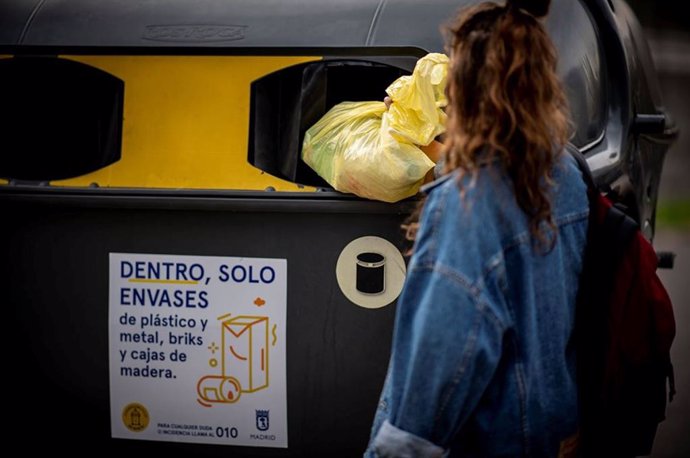 Archivo - Una mujer tira envases en un contenedor amarillo