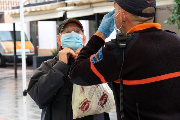 Archivo - Un hombre recibe las indicaciones de cómo colocarse la mascarilla. 