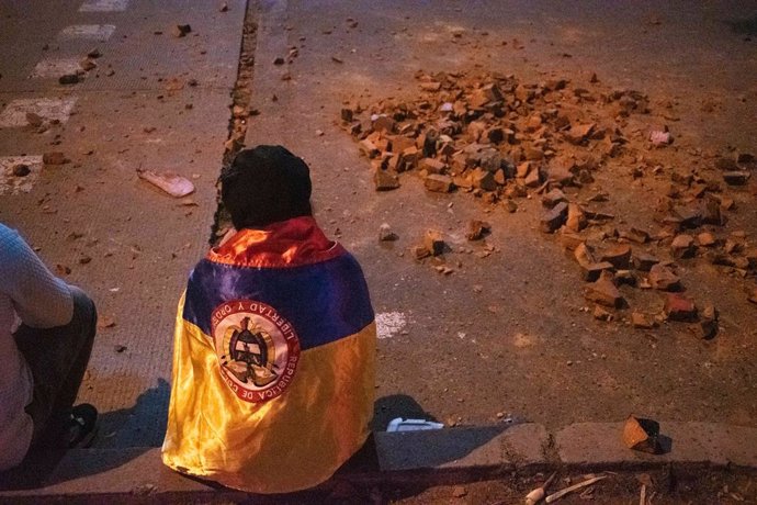 16 June 2021, Colombia, Bogota: A protester wears the Colombian flag on his esplada next to rocks during a new day of anti-government protests against President Ivan Duque's health and tax reforms and police brutality that leaves at least 70 dead in the