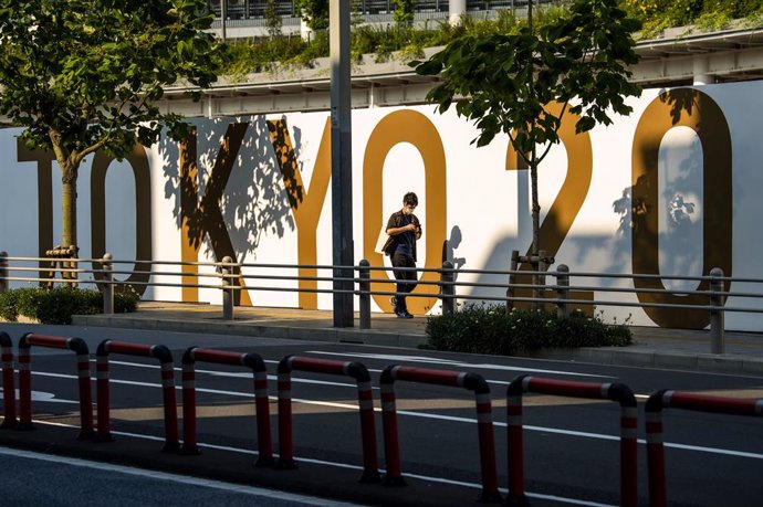 11 June 2021, Japan, Tokyo: A woman walks next to a Tokyo2020 sign at the Olympic Stadium, before the start of the Tokyo 2020 Olympic Games. The Summer Olympics are taking place from 23 July to 8 August 2021. Photo: Rob Walbers/BELGA/dpa