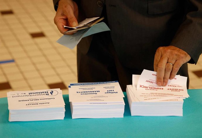 20 June 2021, France, Cucq: A voter takes ballots papers at a polling station in Cucq, Northern France, for the first round of the French regional elections. The regional elections are the last nationwide decision before the French presidential election