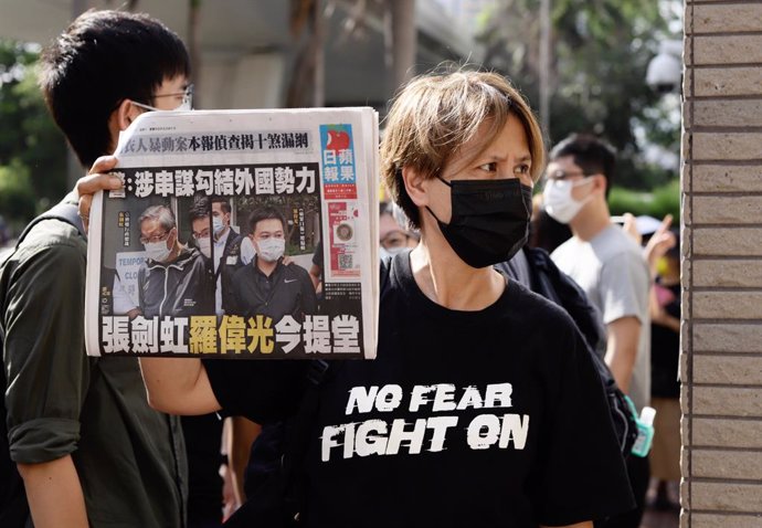 19 June 2021, China, Hongkong: People queue up outside Kowloon West Magistracy to attend audit while a supporter of Apple Daily displaying this morning's copy of Apple Daily's front cover depicting the political trial of the newspaper's executives, publ