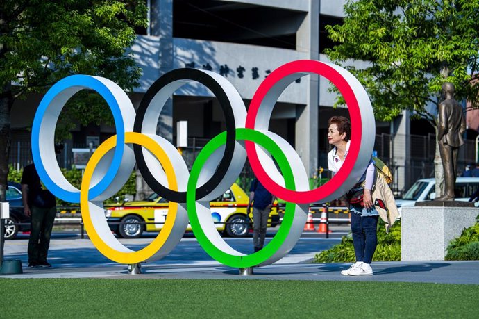 11 June 2021, Japan, Tokyo: Awoman poses behind the Olympic Rings on the Olympic Square, ahead of the Tokyo 2020 Olympic Games. The Summer Olympics are taking place from 23 July to 8 August 2021. Photo: Rob Walbers/BELGA/dpa