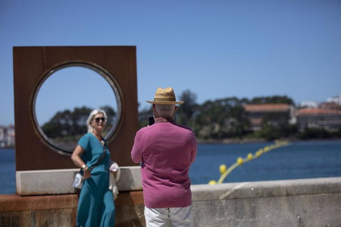 Un hombre echa una foto a una mujer en el paseo marítimo de la playa de Sanxenxo, a 4 de junio de 2021, en Sanxenxo, Pontevedra, Galicia, (España). El aumento de las temperaturas y la progresiva mejora de la situación epidemiológica ha colaborado en que