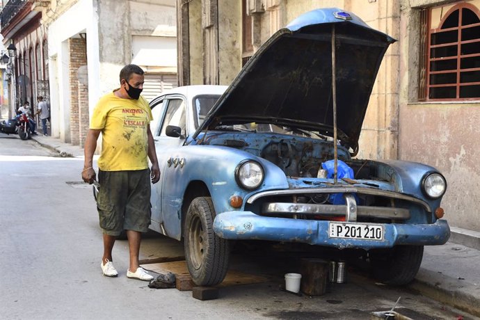 Un hombre con mascarilla arregla un coche en La Habana