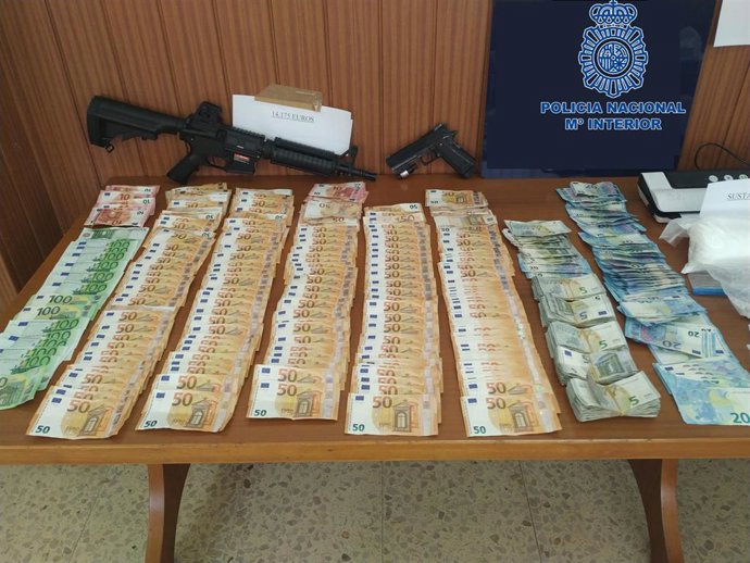 Archivo - El dinero y las armas decomisadas en los registros.