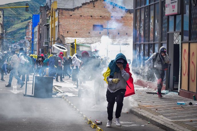 28 May 2021, Colombia, Pasto: Demonstrators run from tear gas during clashes with riot police following a protest against the government of President Ivan Duque Marquez. Colombian President Ivan Duque on Friday night said military assistance would be se