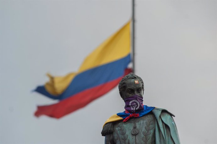 02 June 2021, Colombia, Bogota: The statue of Simon Bolivar located in Plaza de Bolivar with a feminist movement scarf and colombian flag after demonstrators uncovered it as it was covered in cloths to prevent it from being vandalized as Colombians demo