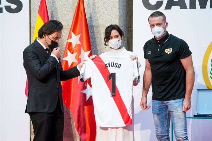 La presidenta de la Comunidad de Madrid, Isabel Díaz Ayuso, posa con una camiseta de fútbol con su nombre y con el presidente del Rayo Vallecano, Raúl Martín Presa, y el capitán Alberto García