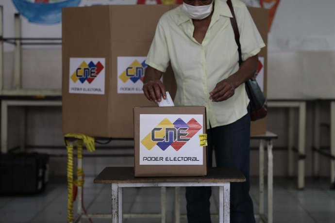 Archivo - 06 December 2020, Venezuela, Caracas: A woman casts her vote into a ballot box inside a polling station during the 2020 Venezuelan parliamentary election. Most opposition parties as well as interim president Guaido expect electoral fraud and h