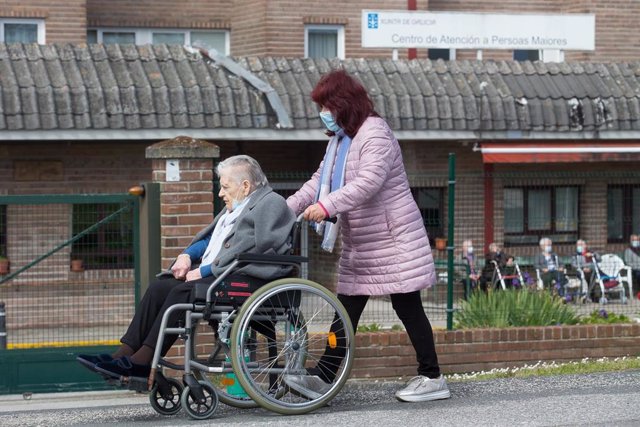 Archivo - Una mujer pasea a una anciana en silla de ruedas, en las inmediaciones de la residencia geriátrica de As Gándaras para visitar a un familiar