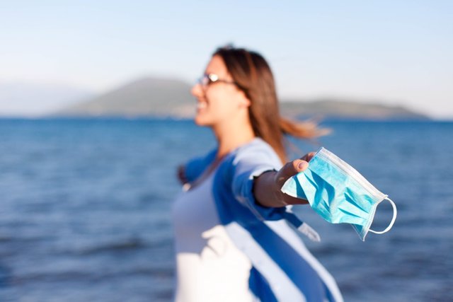 Archivo - Mujer en la playa con la mascarilla en la mano.