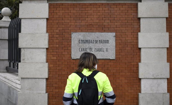 Archivo - Una persona pasa por una señal del Canal de Isabel II, en Madrid (España).