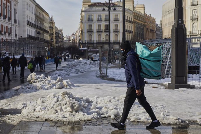 Archivo - Un empleado de Deliveroo camina con su mochila de reparto por la Puerta del Sol nevada tras restablecer parcialmente el servicio, en Madrid, (España), a 15 de enero de 2021. El paso de la borrasca 'Filomena' provocó una gran nevada por lo que 