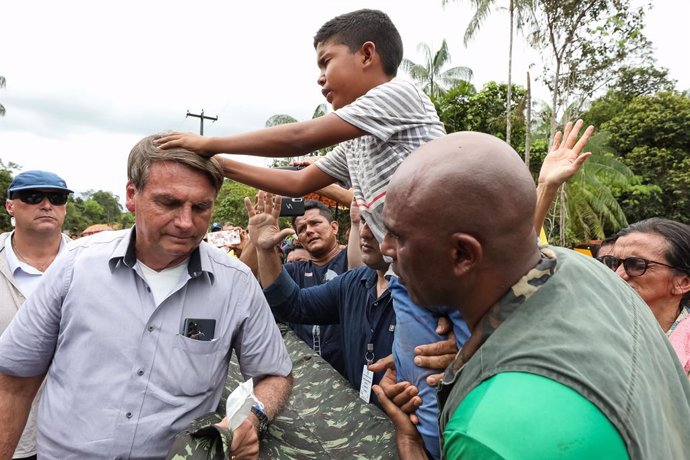 HANDOUT - 27 May 2021, Brazil, Sao Gabriel da Cachoeira: An indigenous child prays for Brazilian President Jair Bolsonaro (L)while attending the inauguration of the Rodrigo e Cibele wooden bridge with indigenous people in Sao Gabriel da Cachoeira. Phot