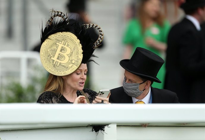 19 June 2021, United Kingdom, Ascot: A racegoer wears a hat with a large Bitcoin symbol on day five of Royal Ascot at Ascot Racecourse. Photo: Steven Paston/PA Wire/dpa