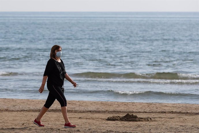 Archivo - Arxiu- Una dona amb mascareta passeja per la platja de la Malva-rosa