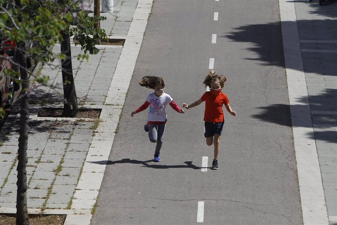 Archivo - Dos niñas corren tras salir a la calle.