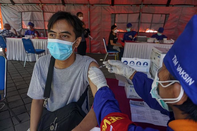 26 June 2021, Indonesia, Denpasar: A health worker jabs a dose of the AstraZeneca coronavirus vaccine to a man. Bali Regional Police performs a Covid-19 mass vaccination at Puputan Renon field. Photo: Dicky Bisinglasi/ZUMA Wire/dpa
