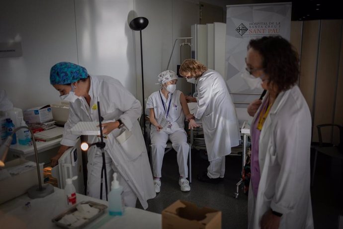 Archivo - Una enfermera vacuna a un profesional sanitario con la vacuna de Pfizer-BioNtech contra el COVID-19 en el Hospital de la Santa Creu i Sant Pau de Barcelona.