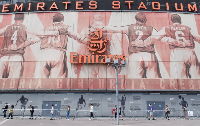 25 June 2021, United Kingdom, London: People queue outside a Covid-19 vaccination centre set up in the Emirates Stadium, the football stadium of the English premier league club Arsenal FC. Photo: Dominic Lipinski/PA Wire/dpa