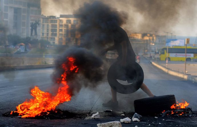 26 June 2021, Lebanon, Beirut: A protestor carries a tire to burn as he blocks a street during an anti-government protest against hard living conditions amid ongoing economic and political crisis. Photo: Marwan Naamani/dpa
