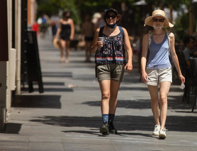 Turistas pasean por el centro de Sevilla provistos de gorras, abanicos y botellas de agua debido a que la capital andaluza ha superado los 40C y por ello se ha activado la alerta amarilla a 08 de junio del 2021, en Sevilla, Andalucía, España
