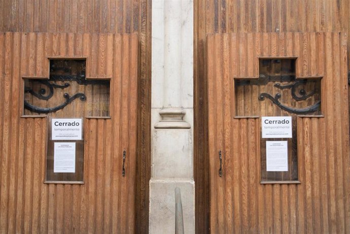 Archivo - Cruces en la puerta de una iglesia con el cartel de 'Cerrado temporalmente' durante la pandemia.