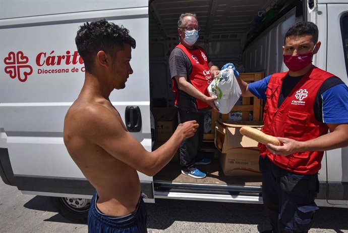 Trabajadores de Cáritas Diocesana reparten alimentos a migrantes que entraron a Ceuta.