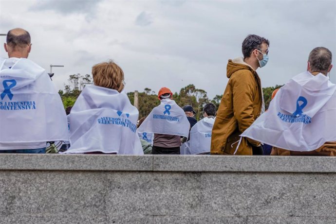 Varias personas con pañuelos reivindicativos, participan en una concentración convocada por el comité de empresa de Alcoa.