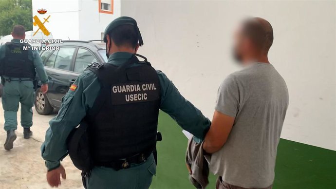 Un agente de la Guardia Civil conduce a un detenido en una operación contra el tráfico de droga en la provincia