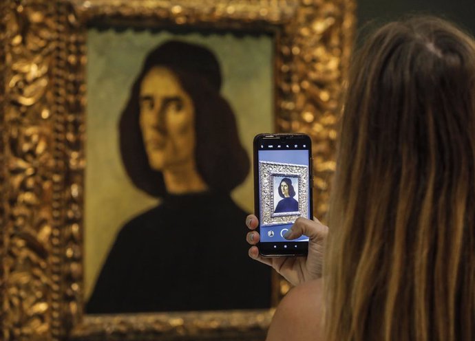 Una persona fotografía el 'Retrato de Michele Marullo Tarcaniota', de Sandro Botticelli en el Museo de Bellas Artes de Valncia. 
