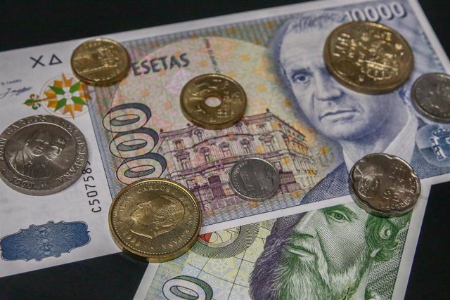 Varias monedas encima de dos billetes de las antiguas pesetas, a 15 de junio de 2021, en Madrid (España). 
