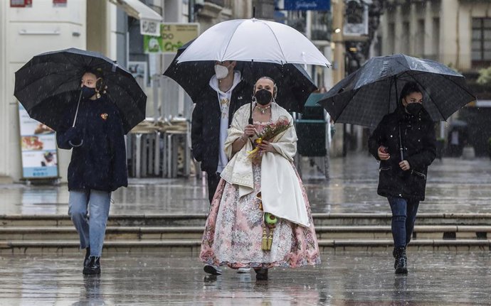 Archivo - Una fallera se dirige a la Basílica de Valencia con un paraguas y un ramo de flores para la Virgen de los Desamparados, en Valencia, Comunidad Valenciana (España), a 18 de marzo de 2021