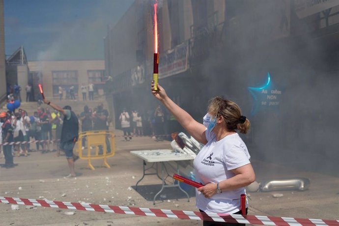 Una mujer sostiene una bengala durante una concentración en conmemoración del año de lucha por la planta de aluminio y los puestos de trabajo de Alcoa San Cervo, en la Praza do Concello de Xove, a 30 de mayo de 2021, en Xove, Lugo, Galicia (España).