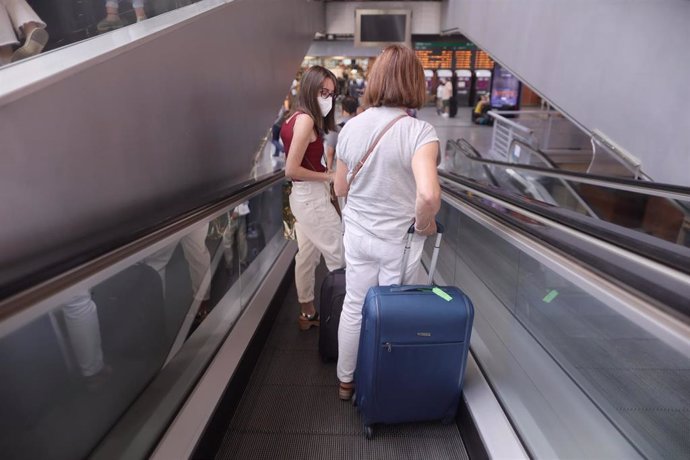 Varias personas bajar en cintas transportadoras, en la estación de Madrid - Puerta de Atocha