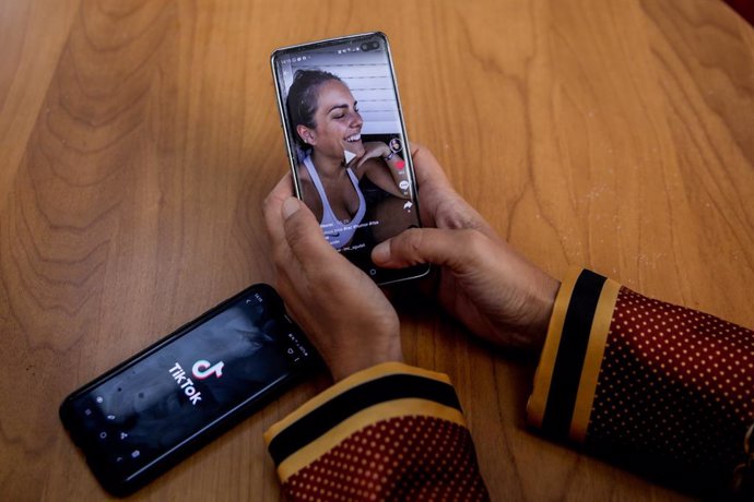 Archivo - Una persona mira en su móvil el vídeo de una joven en la red musical Tik Tok, en Madrid (España), a 22 de septiembre de 2020. TikTok ha publicado este martes su tercer Informe de Transparencia, que recoge la actividad del primer semestre de 20