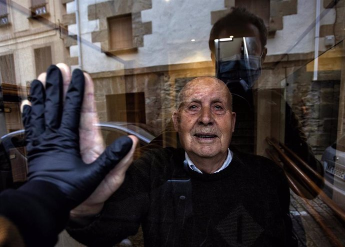 Archivo - Visita a mi abuelo Miguel, de 90 años, durante el confinamiento que saluda a través del cristal del portal.  Huarte, Navarra, 1 de abril, 2020. ( ( Unai Beroiz)